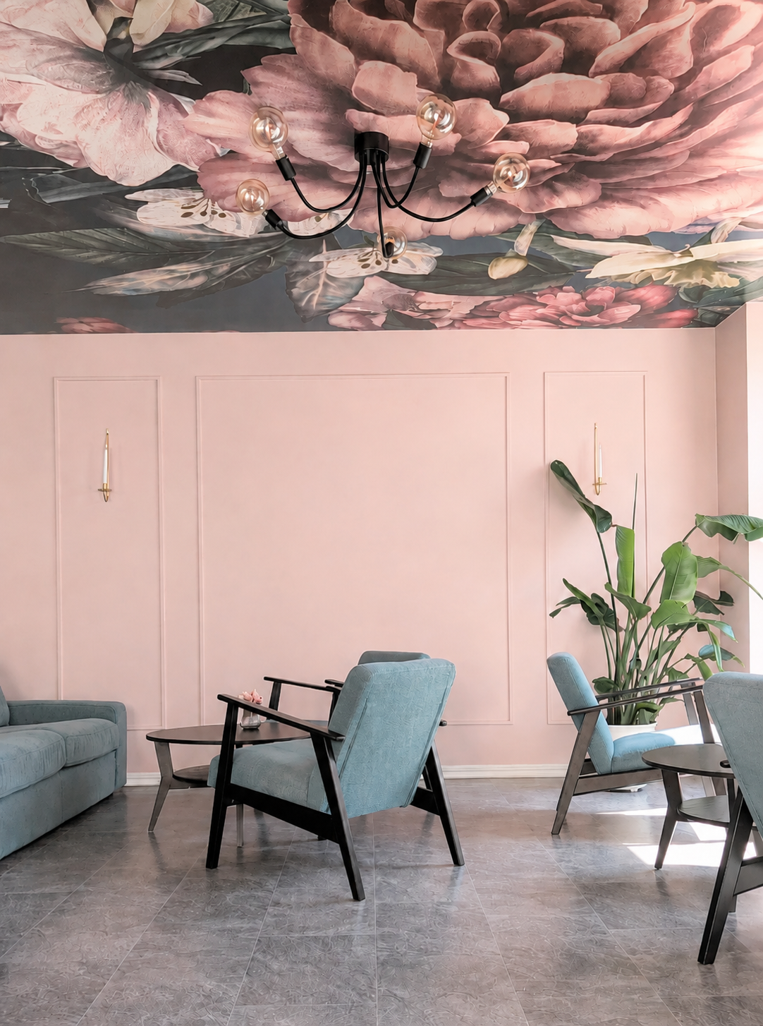 Rosa vägg, blommande takmålning och gröna fåtöljer i loungen på Fika & Relax Lounge