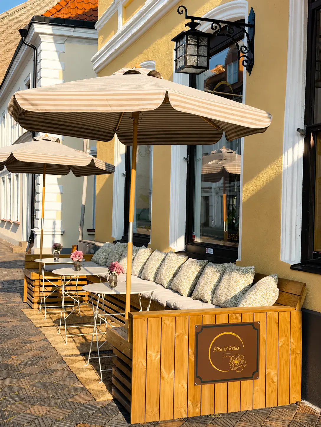 Uteservering med randiga parasoller och loungesoffa i Landskrona
