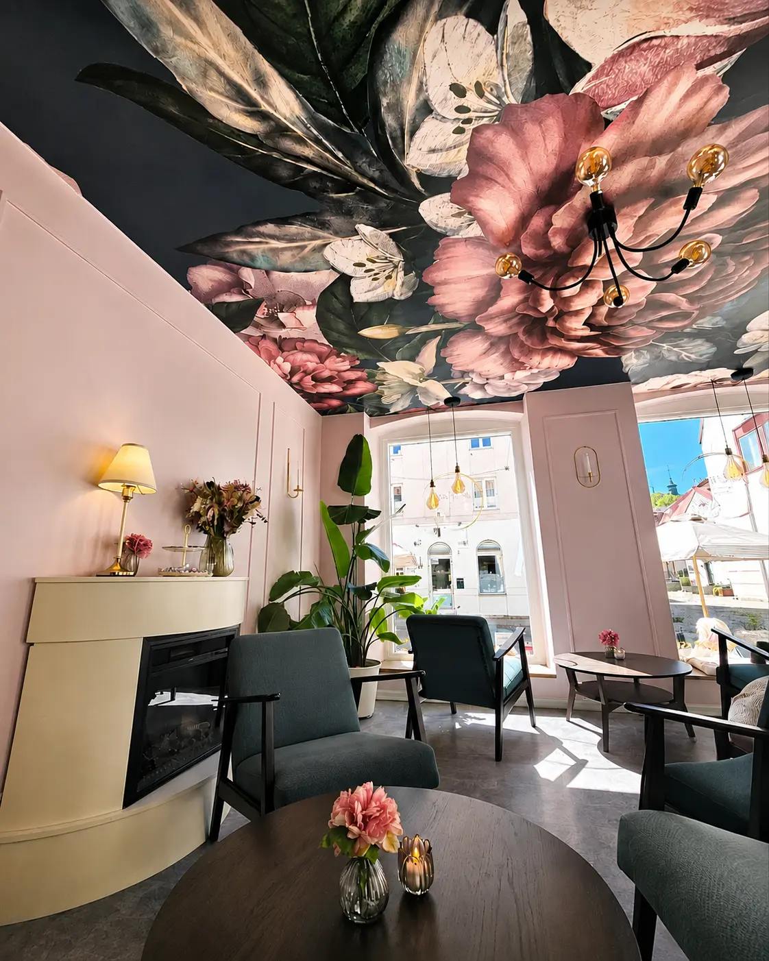 Rosa väggar, blommande tak och fåtöljer i fönstret på Fika & Relax Lounge i Landskrona
