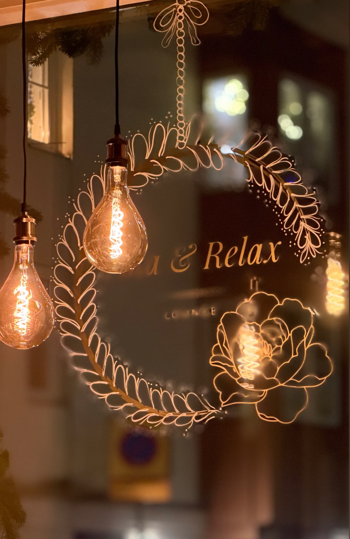 Fika & Relax-loggan i skyltfönstret med glödlampor en kväll i Landskrona